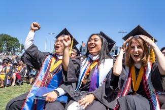 three cheering college graduates